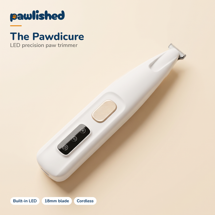 The Pawdicure LED precision paw trimmer - matte white body, gold power button, built-in LED and 18mm blade, on cream